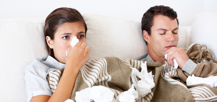 Young couple lie together in bed while they both have the flu