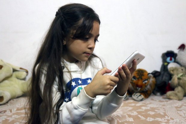 Syrian Bana al-Abed, who with the help of her mother had been posting heartrending tweets in English on life in the besieged eastern districts of Syria's Aleppo, uses a smart-phone to check her Twitter account in her home in east Aleppo, on October 12, 2016. The seven-year-old Syrian girl whose Twitter account from Aleppo gained international attention has fled her home amid heavy fighting, but she and her family are safe for now, her father said on December 6, 2016. / AFP PHOTO / THAER MOHAMMEDTHAER MOHAMMED/AFP/Getty Images