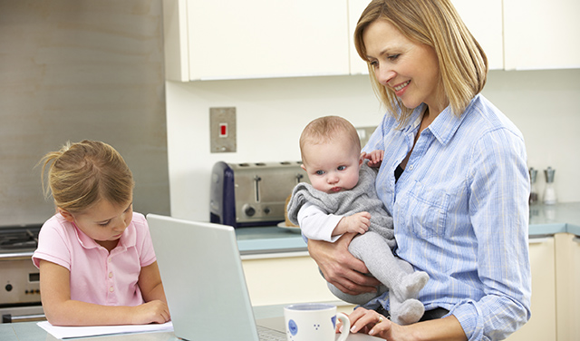 Mother with children using laptop in kitchen