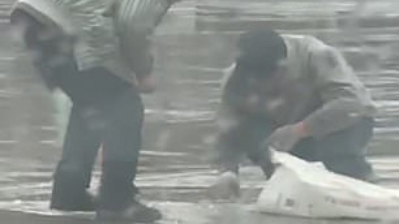 Xhamin që iu ra nga makina, të moshuarit e mblodhën nga rruga nën shi të rrëmbyeshëm (Video)