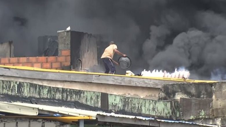 I rrethuar nga zjarri dhe tymi, një burrë shihet duke u ndeshur me flakët – pavarësisht se ishte “i armatosur” me vetëm një kovë