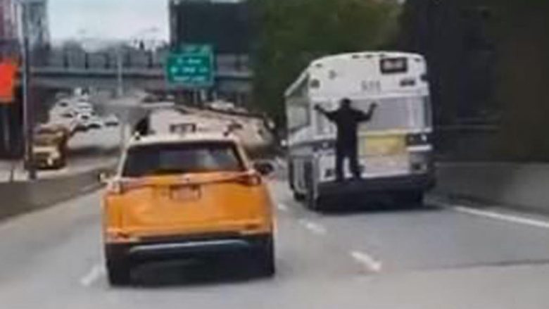 Filmohet burri në Nju Jork duke qëndruar i varur në pjesën e pasme të një autobusi në lëvizje