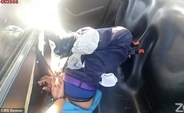 Polici amerikan e mban vajzën me ngjyrë të prangosur me kokë poshtë, në pjesën e pasme të veturës zyrtare