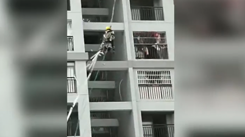 Të lidhur për litarë, dy punëtorët në Kinë lëkunden nga erërat e forta