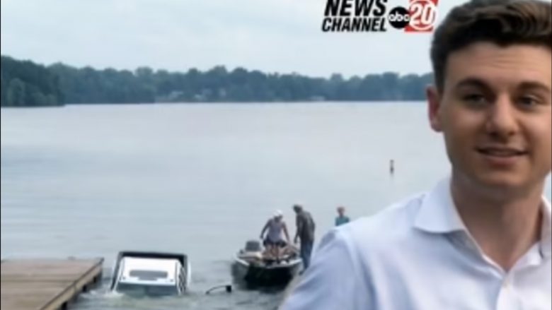 Gazetari po raportonte para liqenit në Illinois, prapa shpinës së tij vetura e re 70.000 dollarëshe rrëshqet nga barka dhe zhytet plotësisht në ujë