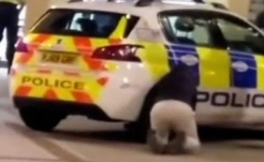 Një burrë shfryn gomat e makinës së policisë ndërsa oficerët blejnë ushqim në një shitore afër në Angli
