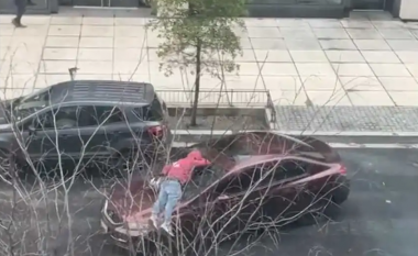 Shoferi i Honda Civic largohet i relaksuar me një njeri të palëvizshëm mbi kofanon e tij