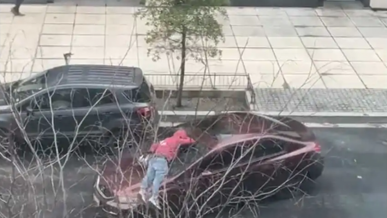 Shoferi i Honda Civic largohet i relaksuar me një njeri të palëvizshëm mbi kofanon e tij