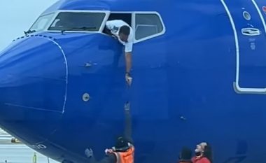 Piloti varet nga dritarja e kabinës së aeroplanit për marrë telefonin e humbur të pasagjerit