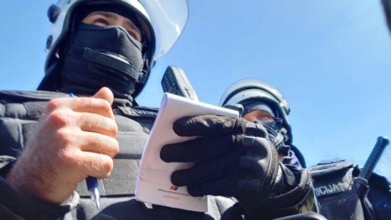 Polici serb në detyrë me fletoren e shënimeve që mban logon e partisë së Vuçiqit