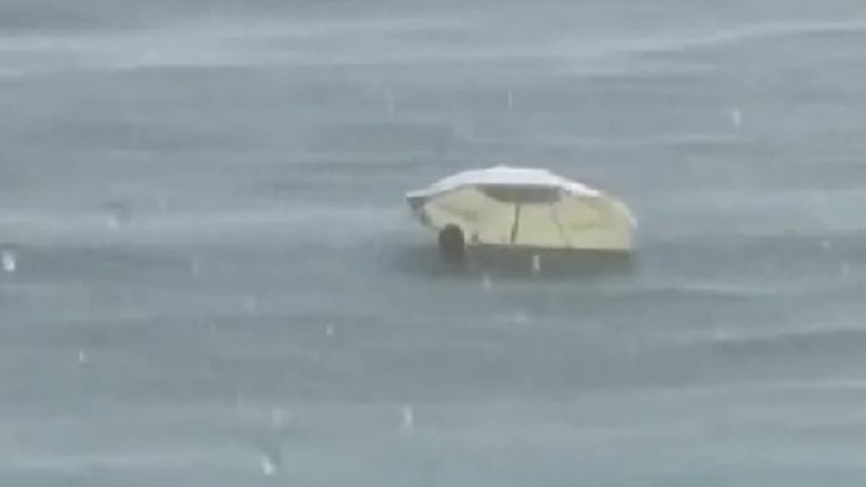 Pavarësisht se binte shi, pushuesi në Ulqin nuk ndalet – futet me ombrellë në ujë