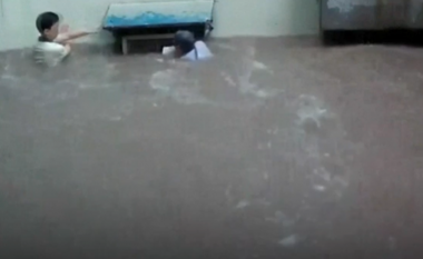 Një grua në Kinë e cila po tërhiqej zvarrë nga vërshimet po mbahej prej një kondicioneri, shpëtohet më pas nga një burrë