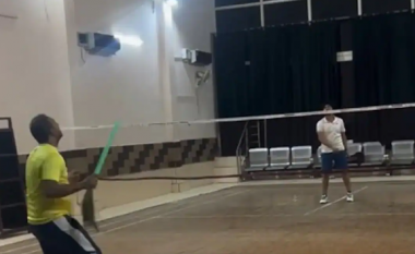 Një burrë shfaq aftësitë e tij teksa luan badminton me fshesë
